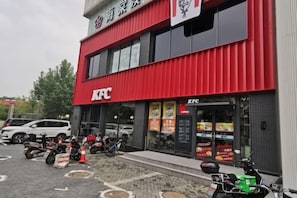 A KFC restaurant with a red exterior, multiple cars parked in front, and several motorcycles.