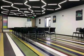 Un salón de conferencias con una pantalla de proyector, sillas y una alfombra a rayas coloridas.