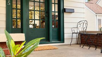 Una casa con puerta principal verde, buzón y un pequeño espacio exterior con mesa y sillas.