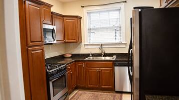 Una cocina con armarios de madera, estufa, microondas, pileta y refrigerador.