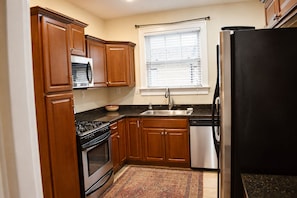 A kitchen with wooden cabinets, a stove, a microwave, a sink, and a refrigerator. - St. Matthew’s - Walk to Shops & Restaurants (Louisville)