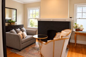 Un salon avec une cheminée, un canapé, un fauteuil et une petite table.