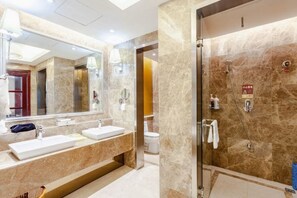 Un baño moderno con un espejo grande, dos lavamanos, una ducha y un inodoro.