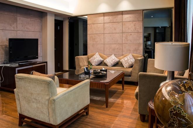 A modern living room with a sofa, armchairs, a coffee table, a TV, and a lamp.