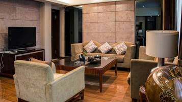 A modern living room with a sofa, armchairs, a coffee table, a TV, and a lamp.