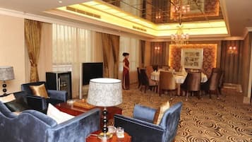 Una camera d'hotel con zona salotto, angolo ristoro e lampadario.