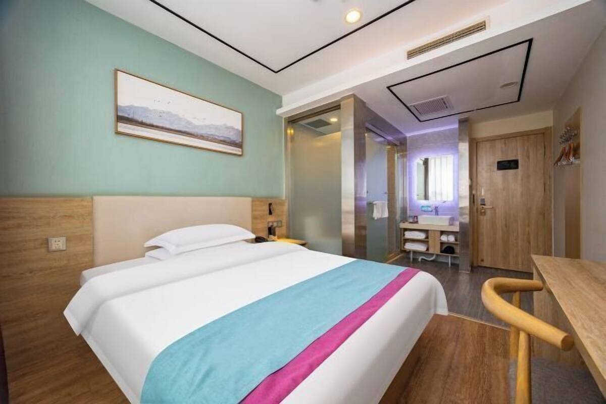Een hotelkamer met een bed, een bureau, een badkamer en uitzicht op een berglandschap.