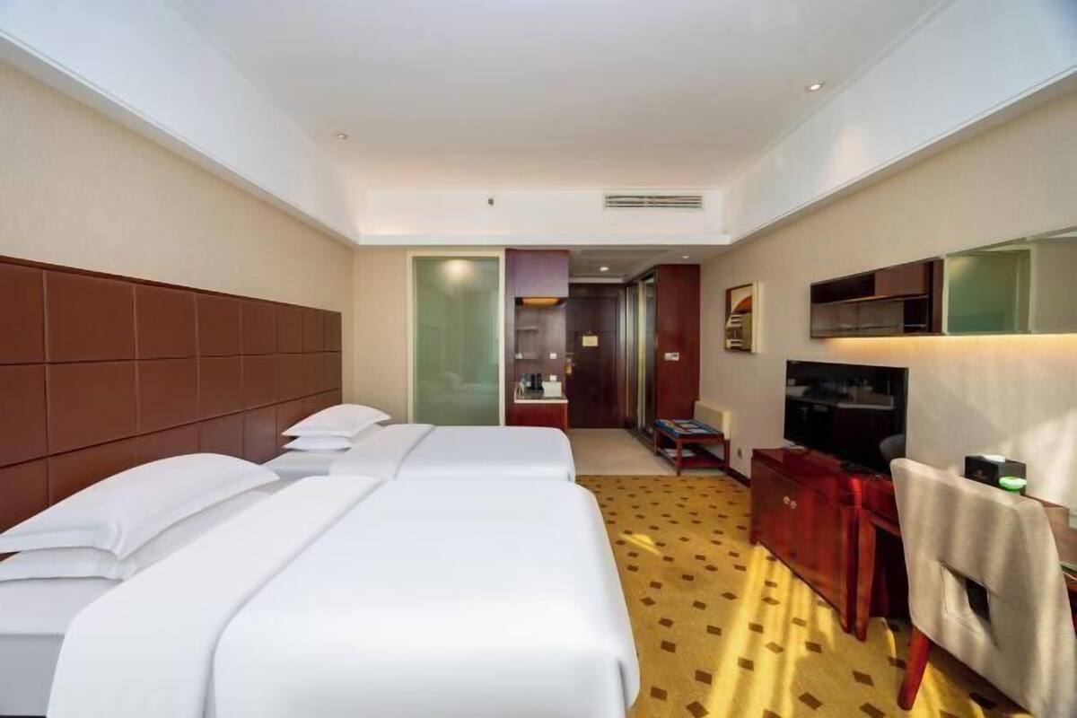 Een hotelkamer met twee bedden, een televisie, een bureau en een stoel.
