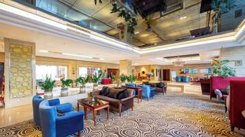 A spacious lobby with a patterned carpet, seating areas, and a reception desk.