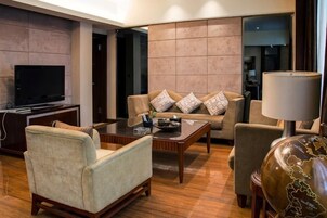 Una sala de estar moderna con un sofá, sillones, una mesa de centro y un televisor.