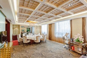 Habitación de hotel con comedor, televisor, alfombra roja y alfombra estampada.