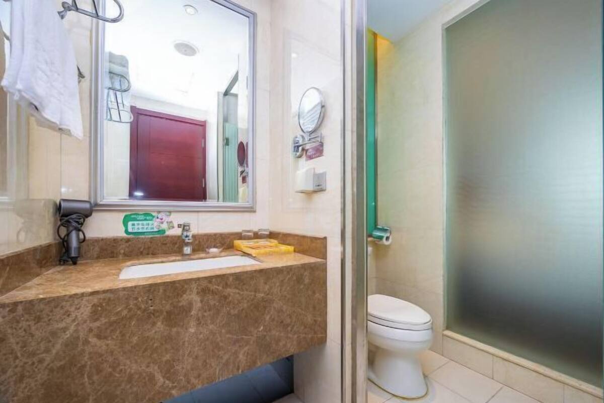 Een badkamer met een marmeren aanrechtblad, een spiegel, een toilet en een douche.