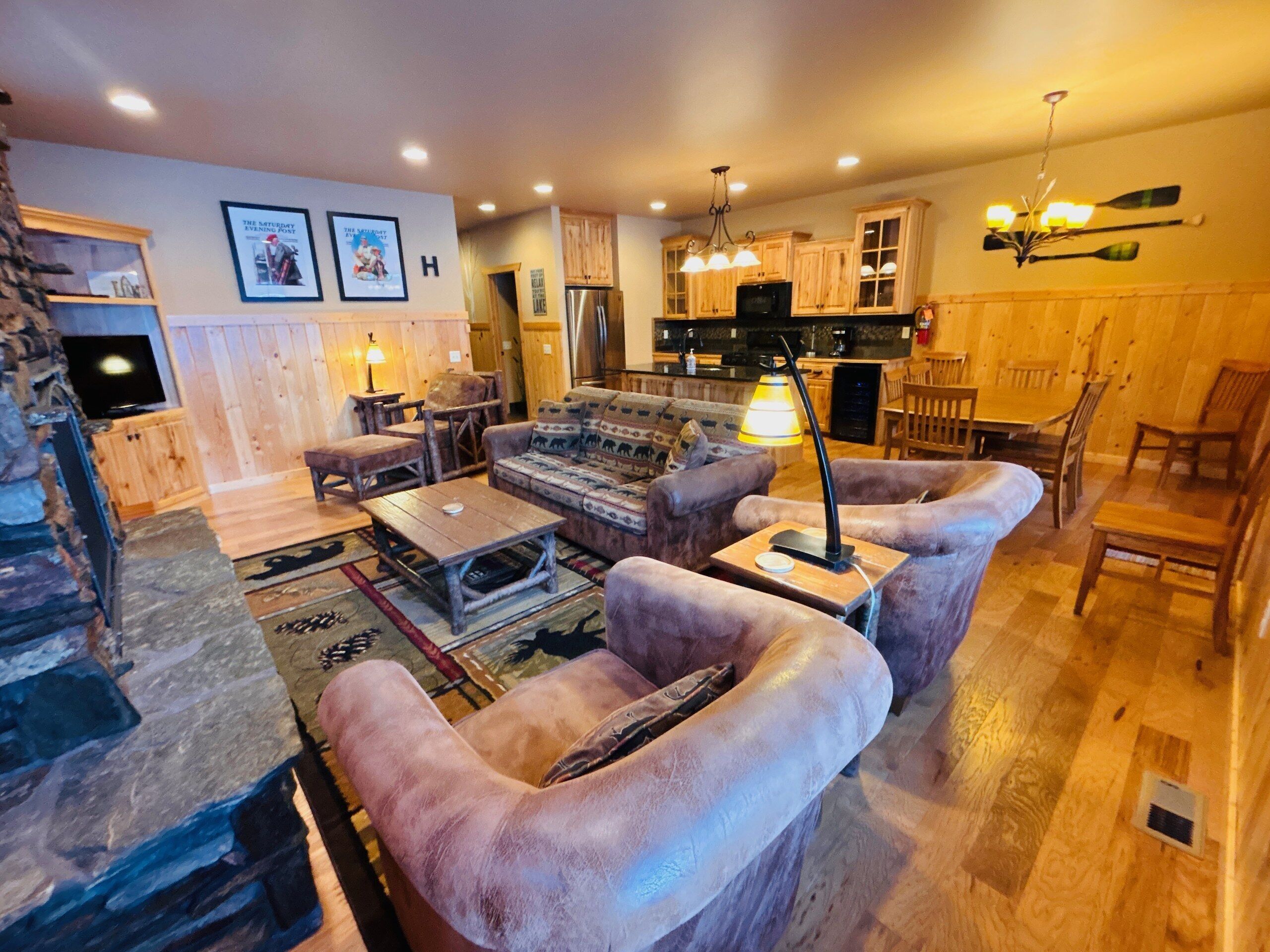 A cozy living room with a fireplace, a dining area, and a kitchen with wooden cabinets.