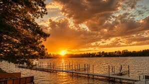 A lakeside view with a wooden dock, a bench, and a sunset. - Lakefront Home on the Whitefish Chain - Outdoor Pool, Pickleball Courts and More (Pequot Lakes)