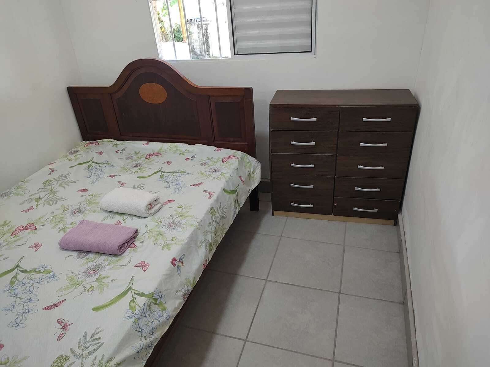 Un dormitorio con cama, cómoda y ventana.