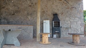 An outdoor stone wall with a built-in brick oven, a stone bench, and a wooden table. - Rancho Dos Anjos Farm in Campinas - Daily Rates, Seasons and Events (Campinas)