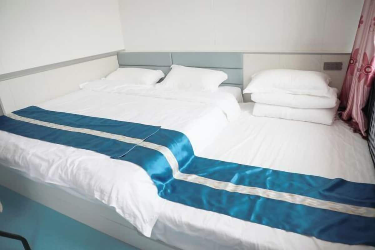 A hotel room with a bed, white bedding, a blue and white striped bed runner, and a headboard.
