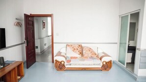 A room with a bed, a wooden desk, a wardrobe, and a door leading to another room. - Huma Hongyue Hotel (Huma)