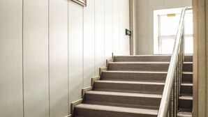 A staircase with a metal handrail, carpeted steps, and a door at the top. - Huma Hongyue Hotel (Huma)
