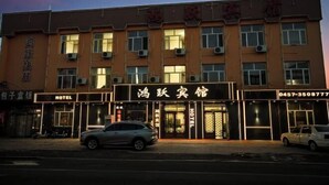 Un hôtel avec une enseigne indiquant « HÔTEL » et un numéro de téléphone. Des voitures sont garées devant.