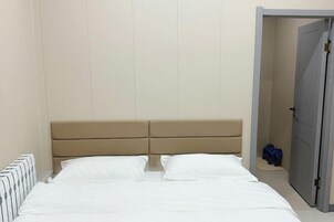 Un dormitorio con una cama, una puerta y un armario pequeño.