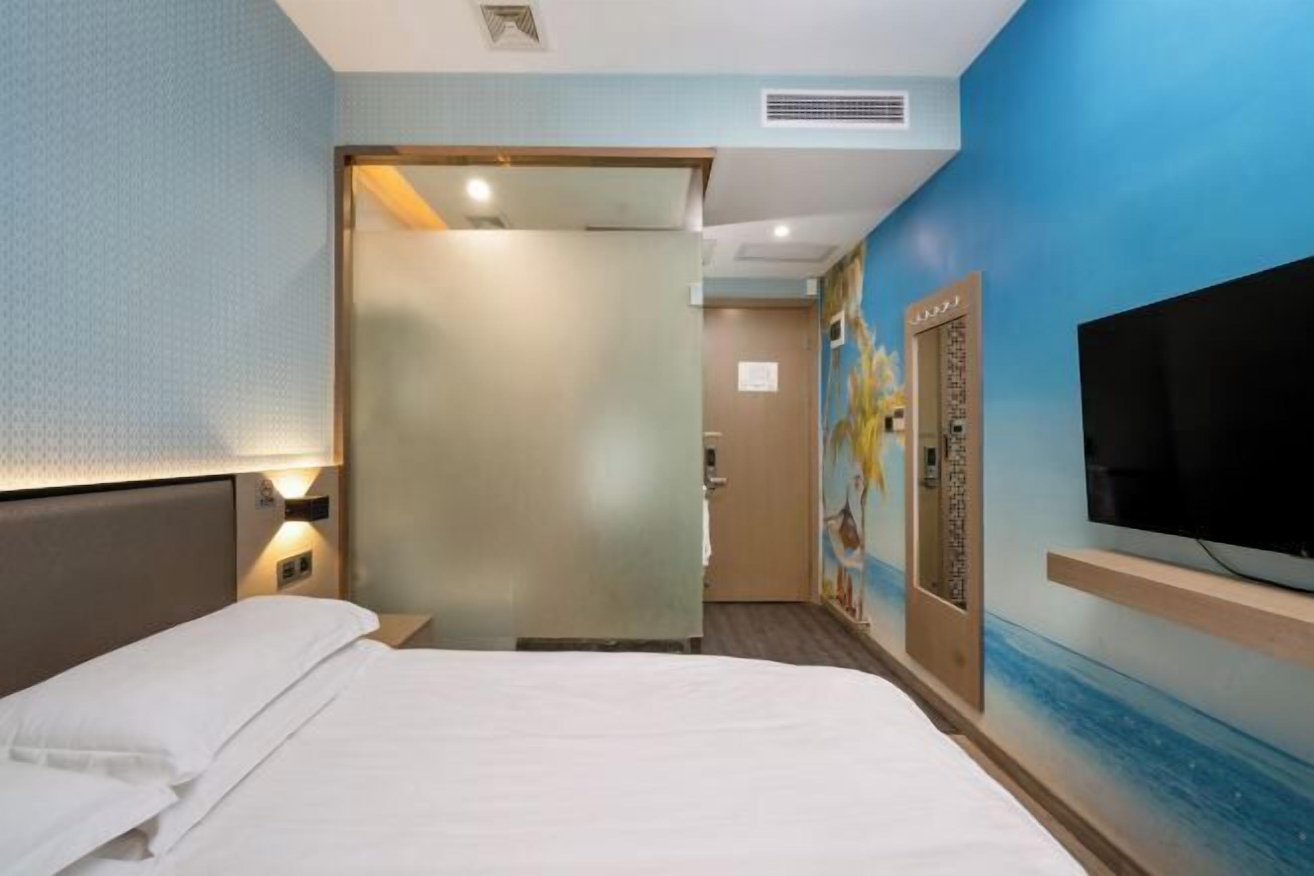 Una habitación de hotel con una cama, un televisor y una pared con un mural.