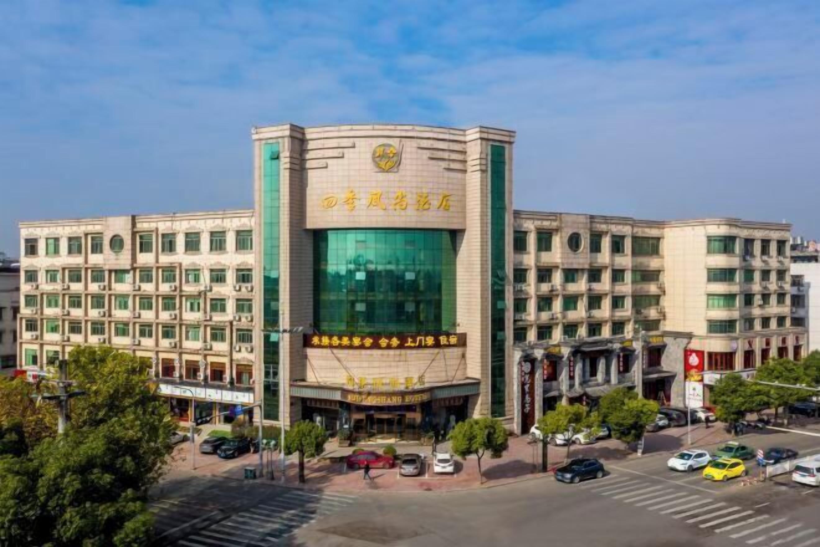 Um hotel com vários andares, uma entrada destacada e sinalização em idioma estrangeiro.