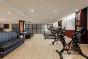 Een fitnessruimte met trainingsapparatuur, een receptie en een zithoek.