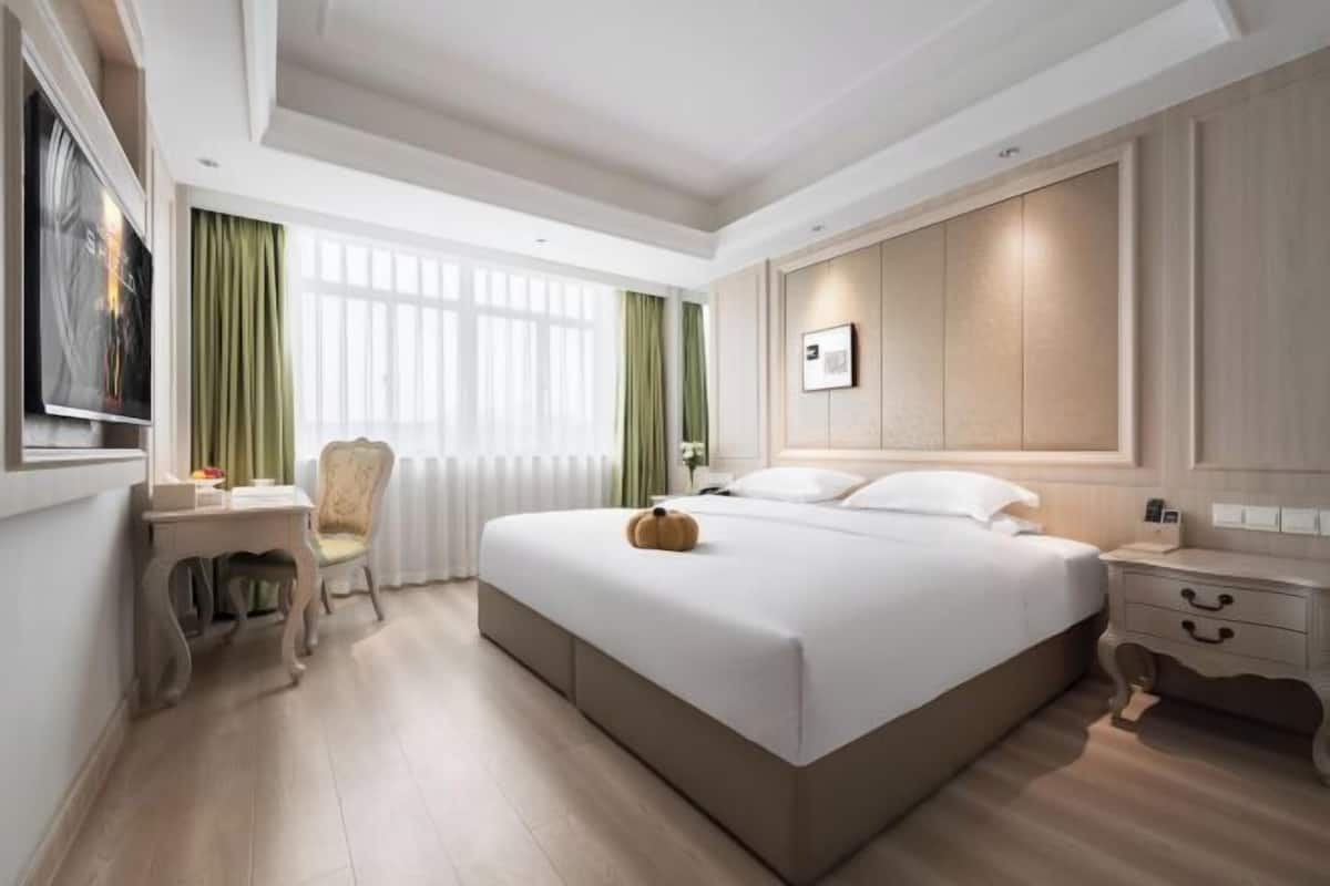 Une chambre d’hôtel avec un grand lit, un bureau, une chaise et un téléviseur.