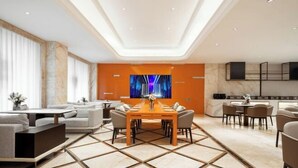 A modern dining area with a central table, sofas, and a TV screen on the wall. - Four Seasons Fashion Hotel (Yongkang South Railway Station Xijinqiao Pedestrian Street) (Yongkang)