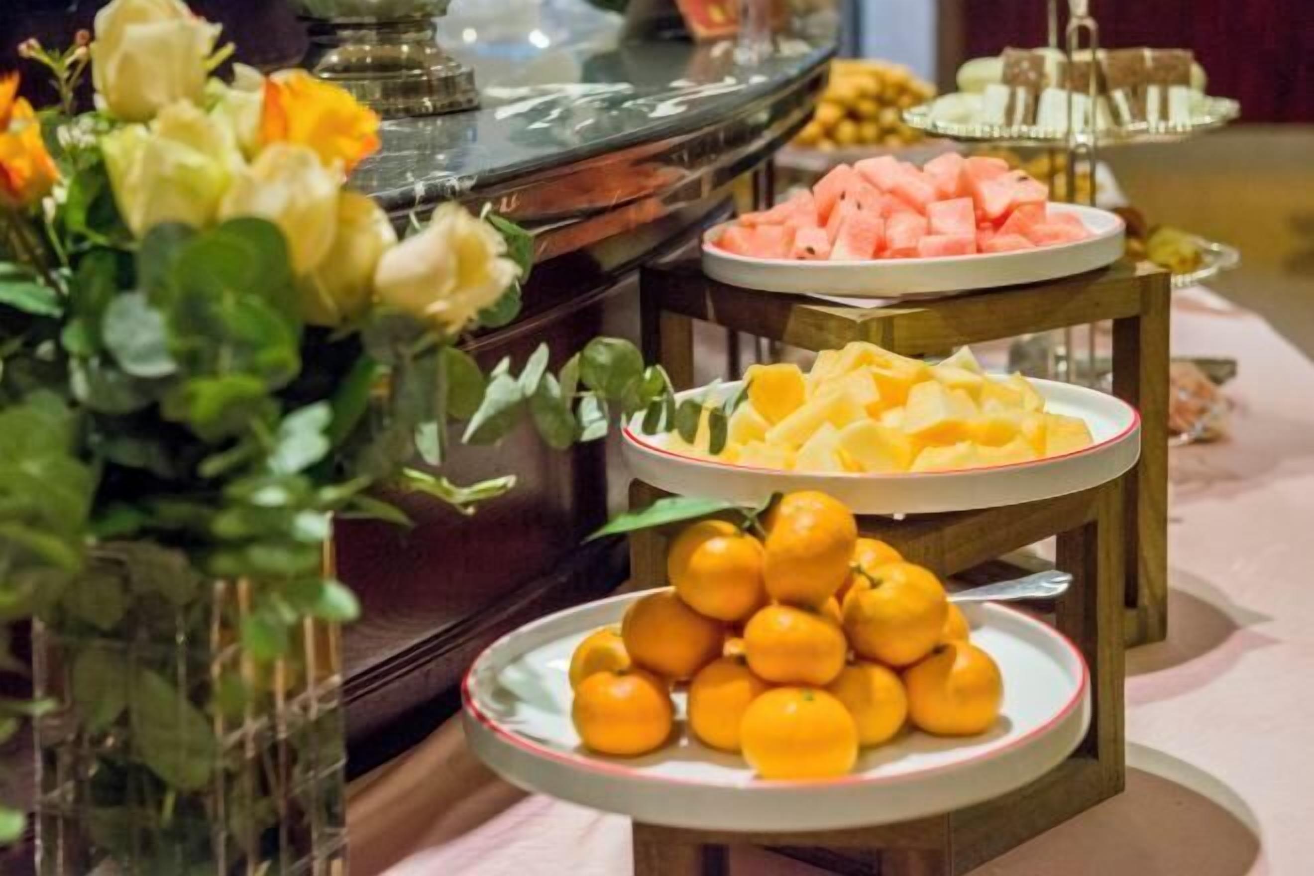 Ein Buffet mit Tellern voller Obst, darunter Wassermelone und Orangen.