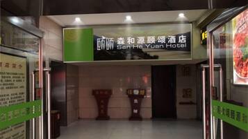 L’entrée de l’hôtel Sen He Yuan, avec une enseigne au-dessus de la porte et une porte en verre.
