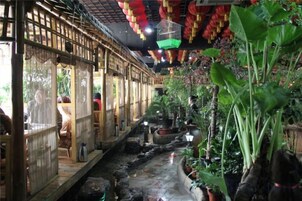 Estructura tradicional de bambú con fuente de agua y plantas en macetas.