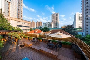 A rooftop patio with outdoor seating, a pool, and high-rise buildings in the background. - Meiyu Hotel (Shanghai)