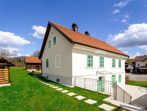 Stairs lead to a front door on this two-story home with a well-manicured lawn and a fenced yard.