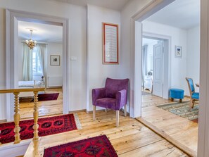 Relax in a spacious living area with a comfortable armchair, modern chandelier, and dining area.