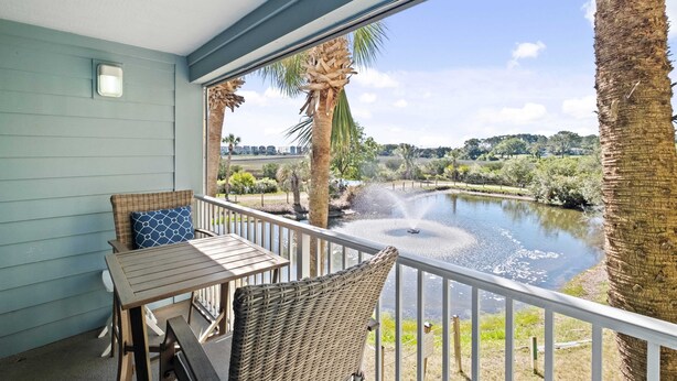 Un balcon agrémenté de meubles en osier, avec vue sur un lac et un palmier.