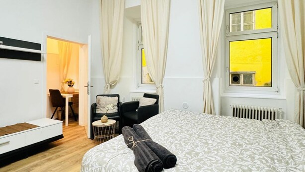 Une chambre à coucher avec un lit, un bureau, une chaise et une fenêtre avec des rideaux.