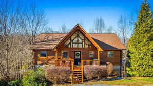 Eine Blockhütte mit einer Veranda, einer Holztreppe und einem Schild, das anzeigt, dass es sich um eine Lodge handelt.
