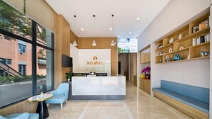 A hotel reception area with a marble counter, blue seating, and a bookshelf. - Jiu Ju Hotel (tongnan South Road) (Shanghai)