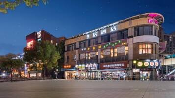 A multi-story hotel with a prominent signage, a large open plaza in front, and various shops on the ground level.
