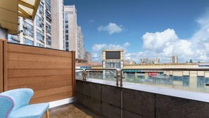 A balcony with a view of high-rise buildings, a wooden partition, and a blue chair. - Jiu Ju Hotel (tongnan South Road) (Shanghai)