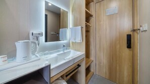 A modern bathroom with a sink, mirror, and wooden cabinets. - Jiu Ju Hotel (tongnan South Road) (Shanghai)