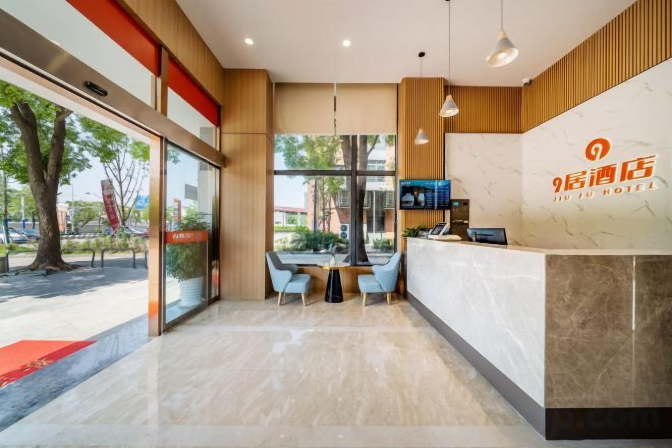 A hotel reception area with a reception desk, seating, and a view of the outdoors.