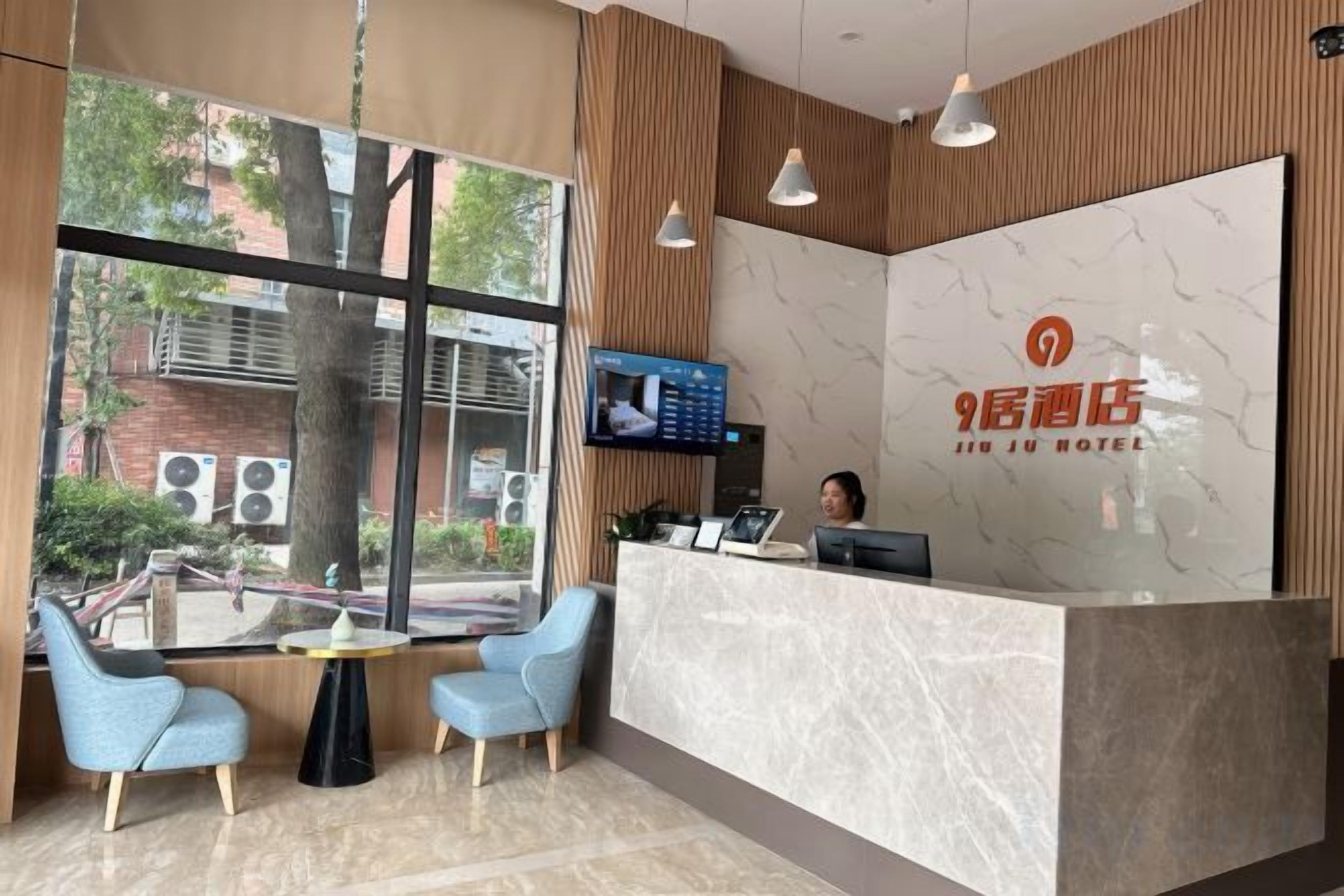 A hotel reception area with a marble counter, a television, and seating.
