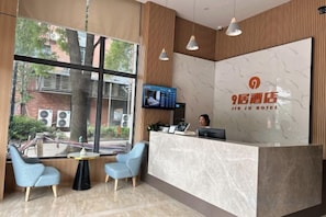 A hotel reception area with a marble counter, a television, and seating. - Jiu Ju Hotel (tongnan South Road) (Shanghai)