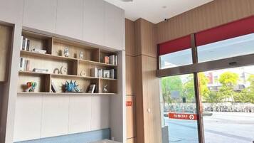 A reception area with a counter, shelves with various items, and a view of the street outside.