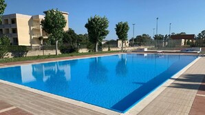A rectangular swimming pool with clear blue water, surrounded by a tiled deck and a low brick wall. - La Conchiglia  - Piscina e Animazione gratuita (Bernalda)