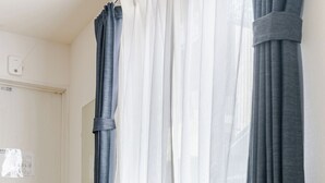 Una habitación pequeña con una mesa redonda y una silla negra perforada.