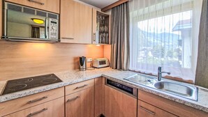 Eine moderne Küche mit Holzausstattung, einer integrierten Mikrowelle, einem Toaster und einem Fenster mit Vorhängen.